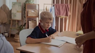 Tanımlanamayan annenin elleri, oğluna ev ödevini düzgün yapmasını söylüyor.