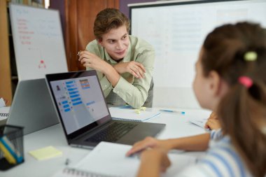 İş arkadaşlarıyla iş görüşmesi yapan, tartışma ve beyin fırtınası yapan bir adam. Görünür dizüstü bilgisayar ve yazılı notlar profesyonel ayarları vurgular