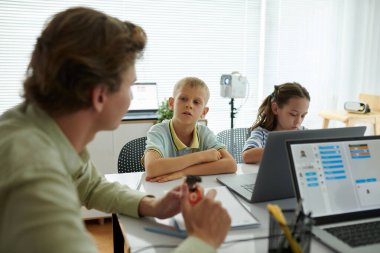 Modern sınıfta çocuklarla bilgisayar ve eğitim materyalleriyle uğraşan öğretmenler.