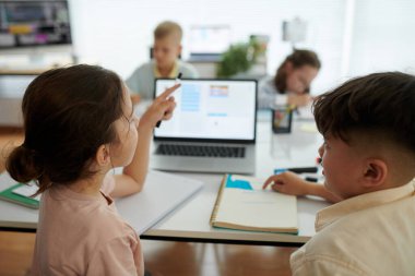 Modern masadaki elektronik cihazları kullanırken akademik görevlerde işbirliği yapan bir grup çocuk aktif katılım ve katılımcılığı teşvik ediyor