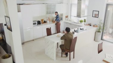 Genç Asyalı karı ve kocanın sabah kahvaltısını ev mutfağında yerken çekilmiş statik kamera görüntüleri.