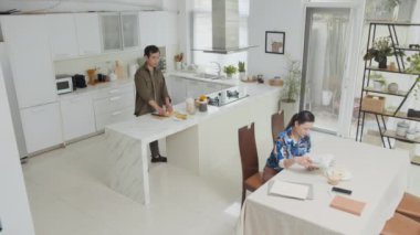 Asyalı adamın karısına kahvaltı hazırlarken geniş açılı görüntüsü.