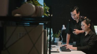 Asya kökenli iki güvenlik görevlisinin kamera arkası görüntüleri. Monitörleri kontrol ediyor ve telsiz kullanıyor.