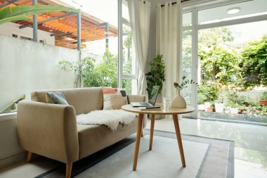 Rahat kanepesi ve büyük pencereleri olan modern oturma odası.