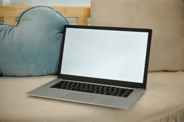 Oturma odasındaki kanepede dizüstü bilgisayarın yakın çekimi.