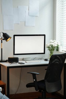 Çalışma odasının duvarında bilgisayar monitörü ve kağıtları var.