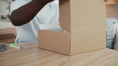 Neşeli Afro-Amerikan bir adamın yeni deri ayakkabılarını evinde paketlediği için sevinçten havalara uçar.