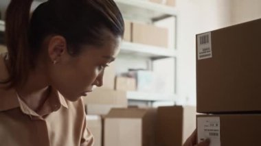 Karton kutularda dizüstü bilgisayarda kargo ve daktilo için tarayıcı kullanırken genç Asyalı teslimat elemanının görüntüsünü eğ