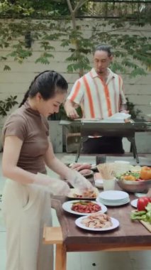 Çeşitli arkadaşlardan oluşan dikey bir grup açık hava partisinde barbekü için yemek hazırlıyor.