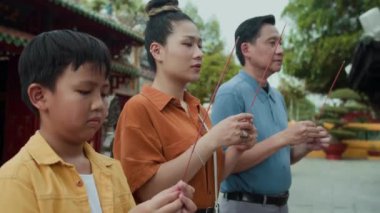 Genç oğlu ve ailesinin eski Asya tapınağını ziyaret ederken dua edişleri düşük açılı bir bakış açısı