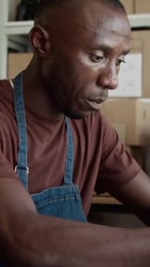 Depoda dizüstü bilgisayarda çalışan siyah dağıtım servisi yöneticisinin dikey görüntüsü