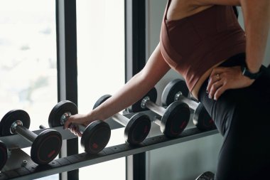 Spor salonunda dambılları olan zayıf kadın eğitimine yakın çekim.