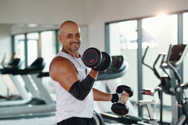 Spor salonunda spor yaparken dambılları kaldıran sporcu portresi