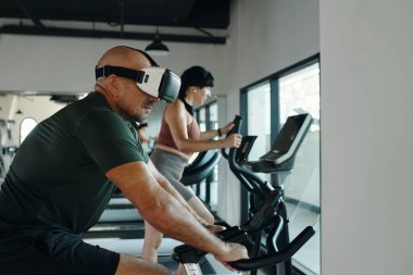 Spor salonunda VR gözlükleriyle spor yapan bir adam.