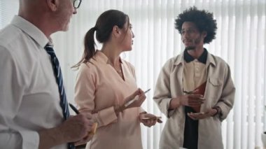 Modern ofisteki proje üzerine beyin fırtınası yapan üç farklı pazarlamacının çekimini indirin.