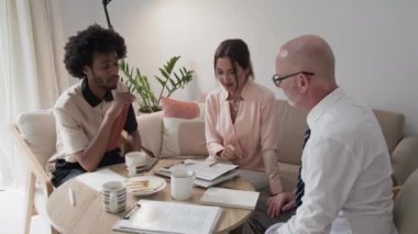 Ofisteki sehpada otururken müdürlerden oluşan orta boy yaratıcı bir ekibin ara vermesi.