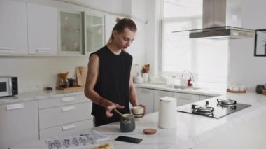 Orta boy beyaz erkek moda tasarımcısının ev mutfağında kahvaltı hazırlarken.