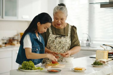 Büyükannem torununa mutfakta sandviç pişirmeyi öğretiyor.