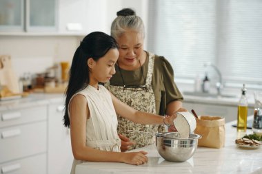 Büyükannem torununa pasta için hamur yapmayı öğretiyor.