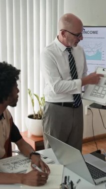 Ofisteki yeni başvuru arayüzü konusunda meslektaşlarına danışan orta yaşlı Kafkas proje yöneticisinin dikey görüntüsü