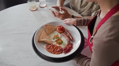 Garsonun Cafe 'deki müşteriye kahvaltıyla servis yaptığı yüksek açılı manzara.