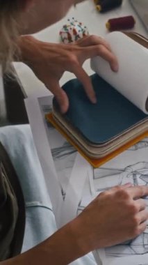 Yeni kıyafet koleksiyonu için elbise ve renk seçen terzinin dikey görüntüsü