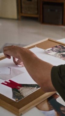 Moda tasarımcısının küçük bir stüdyoda otururken ruh hâli tahtası hazırladığı dikey çekim.