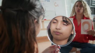 Hintli ergen çocuk eğitimi, kadın öğretmenle logopedik derslere katılırken aynanın karşısında telaffuz sesi çıkarır.