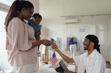 Seçim günü oy verdiği için vatansever rozeti olan genç bir anne.
