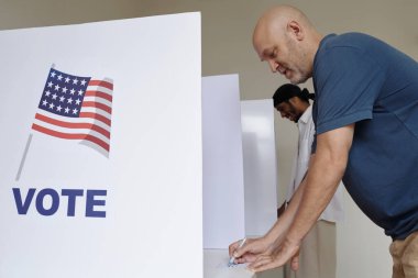 Seçim gününde form dolduran ve kabinde oy kullanan erkekler