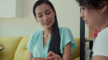 Manikür salonundaki prosedürle ilgili danışmanlık yaparken genç kadınların ellerini tutarken aşağı eğil.