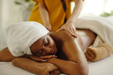 Spa merkezinde rahatlatıcı masajdan hoşlanan bir kadın, havluyla kaplı bir masada uzanmış, sakinleştirici tedavi görüyor, huzurlu bir ortamda sergileniyor.