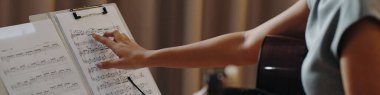 Antrenman sırasında notalar ve arka planda bir gitarla düzenlenmiş notalar üzerinde notalara işaret ederek