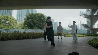 Şehirdeki Asyalı genç insanların hip hop dansı provası yapıp dışarıda dans ettikleri çok uzak bir plan.