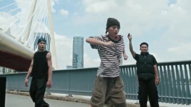 Asyalı kadın serbest stil dansçı eğitimine şehrin arka planında arkadaşlarıyla birlikte düşük açılı bakış açısı