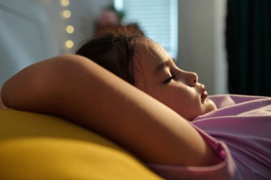 Yatak odasında yastıkta uyuyan kızın yakın çekimi.