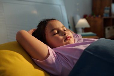 Yatak odasında rahat bir yatakta dinlenen tatlı bir kız.