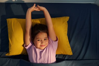 Yüksek açılı küçük kız sabah uyandığında yatağında