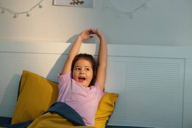 Odada yatarken kollarını kaldıran bir kız.