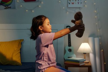 Küçük kız uyumadan önce oyuncağıyla oynuyor.