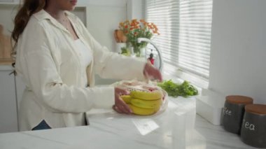 Günlük giysili bir kadının taze ürünleri mutfak çantasından çıkarırken çekilmiş bir fotoğrafı.