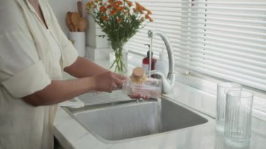 Mutfak lavabosunda bardakları yıkarken anonim bir kadının fırça kullanması.