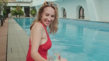 Yaz tatilinde havuz başında dinlenirken arkadaşlarıyla kadeh tokuşturan genç beyaz kadın POV 'u