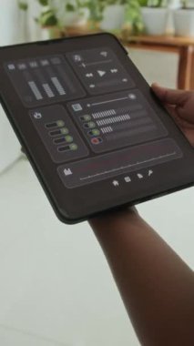 Dijital tablet üzerindeki uygulamayı kullanarak akıllı ev sistemini kontrol eden tanımlanamayan kişinin dikey görüntüsü