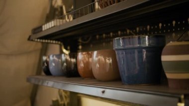 Çanak çömlek atölyesinde raflarda bulunan el yapımı vazolar ve bardaklar.