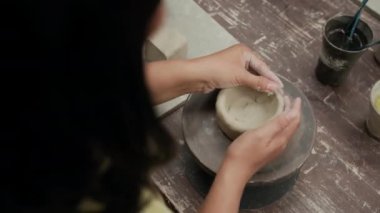 Yüksek açılı, tanınmayan bir kadının atölyede kil çömlek yontması.