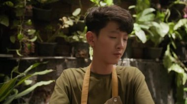 Asya 'lı bir gencin atölyede ders sırasında kilden ot yaparken çekilen pozu.