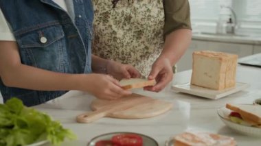 Tanımlanamayan çocuk ve kadının mutfak tezgahında birlikte kahvaltı hazırlarken çekilmiş görüntüsü.