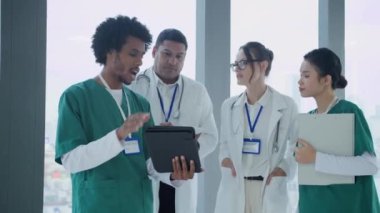 Modern hastanenin koridorunda iletişim kuran üniformalı doktorlardan oluşan orta ölçekli bir grup.