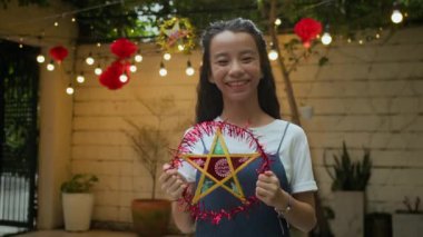 Sonbahar ortası festivali kutlaması sırasında arka bahçede madalyalı yıldız tutan neşeli Vietnamlı genç kız portresi, yıldız üzerine yazı demek sonbahar ortası festivali demek.
